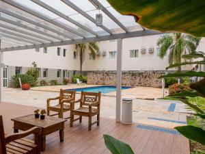 un patio con mesa, sillas y piscina en Ibis Styles Campinas Alphaville, en Campinas