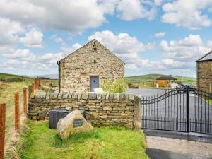 ein Backsteingebäude mit einem Tor und einer Steinmauer in der Unterkunft Rita's Roost, Lancs, tranquil with amazing views in Burnley