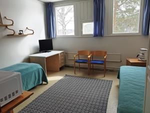 a bedroom with two beds and a desk and a tv at Vanha Koulu in Suolahti