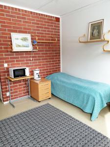 een slaapkamer met een bed en een bakstenen muur bij Vanha Koulu in Suolahti