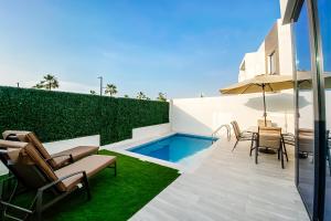 patio ze stołem i krzesłami oraz basenem w obiekcie Luxury Villas with Beach Access by VB Homes w mieście Ras al-Chajma