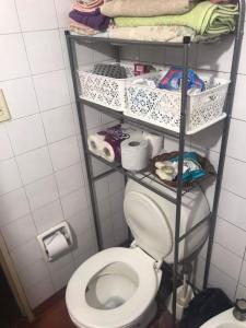 baño con aseo y estante con artículos de aseo en Habitacion Super Comoda en Casa Particular en Tandil
