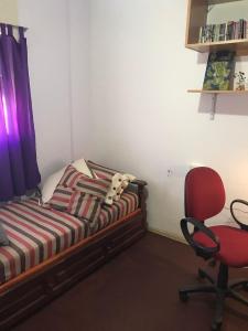 ein Schlafzimmer mit einem Bett und einem roten Stuhl in der Unterkunft Habitacion Super Comoda en Casa Particular in Tandil