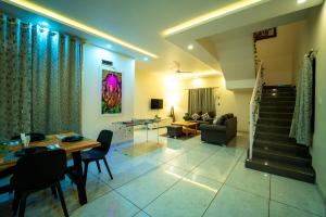 a living room with a table and chairs and a staircase at Spicy Mango Villa Gardena - Luxurious Villa In Karjat in Thākurvādi
