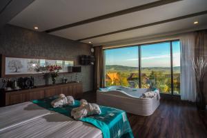 a bedroom with two beds and a tub and a window at Castellum Hotel Hollókő in Hollókő