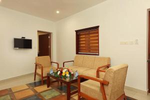 ein Wohnzimmer mit einem Sofa, 2 Stühlen und einem Tisch in der Unterkunft Eloor Tourist Home in Ernakulam
