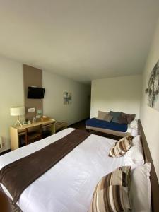 una camera con un grande letto e una scrivania di Hôtel-Restaurant La Belle Poule - Contact Hotel a Rochefort