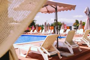 a row of chairs and umbrellas next to a swimming pool at Nafron Hotel in Prizren