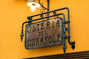 Znak wiszący na żółtej ścianie w obiekcie Antica Osteria del Mirasole w mieście San Giovanni in Persiceto