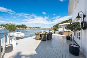 a deck with furniture and a boat on the water at Luxurious Boathouse with Private Dock in the Best Location in Arendal in Arendal