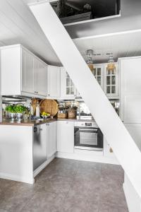 a kitchen with white cabinets and stainless steel appliances at Luxurious Boathouse with Private Dock in the Best Location in Arendal in Arendal
