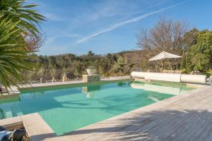 a swimming pool with blue water and an umbrella at Bastide Rocquejeanne in Murs