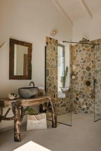 a bathroom with a sink and a stone wall at Spathes Suites Kefalonia - Luxury Suites in Ratzaklíon