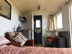 a bedroom with a bed and a kitchen with a sink at Ewe With A View Sea View Shepherds Huts in Breage