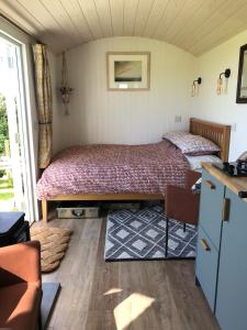 Ewe With A View Sea View Shepherds Huts في Breage: غرفة نوم بسريرين وطاولة واريكة