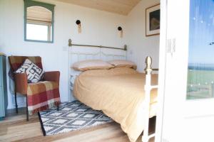 1 dormitorio con 1 cama y 1 silla en Ewe With A View Sea View Shepherds Huts, en Breage