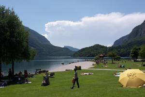 Un groupe de personnes assises sur l'herbe près d'un lac dans l'établissement Monolocale a Molveno, à Molveno