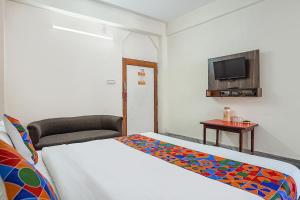 a bedroom with a bed and a chair and a television at FabHotel New Shanti in Allahābād