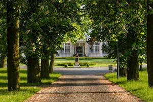 un chemin devant une maison blanche avec des arbres dans l'établissement Hotel Pałac Romantyczny, à Turzno