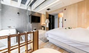 Hotel Yeogiuhtte SeoDaegu في دايغو: غرفة نوم مع سرير أبيض كبير وحوض استحمام