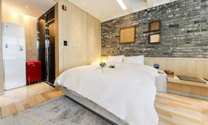 Hotel Yeogiuhtte SeoDaegu في دايغو: غرفة نوم بسرير ابيض كبير وجدار من الطوب