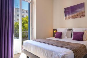 ニースにあるオテル ド ラ フォンテーヌのベッドルーム1室(大型ベッド1台、紫色の枕付)