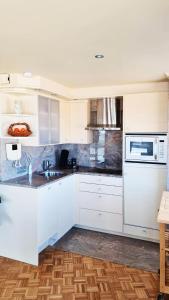 a kitchen with white cabinets and a microwave at Maui - zeezichtappartement te Oostende in Ostend