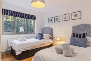 a bedroom with two beds and two windows at Oaktree Lodge - Luxury Cottage, Hot Tub, Sea Views in Saundersfoot