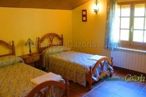 a bedroom with two beds and a table and a window at CASA CAÑADA DEL PUERTO in Cazorla