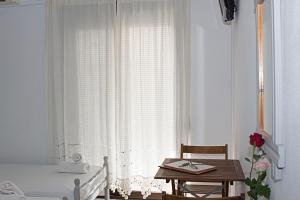 a bedroom with a bed and a table and a window at La Pensione Skiathos in Skiathos Town