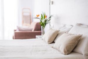 a white bed with pillows and a vase with a flower at Dunas Club - Hotel & Apartamentos in Corralejo