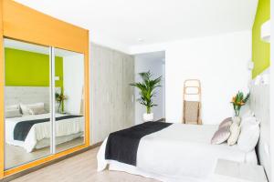 a bedroom with a white bed and a large mirror at Dunas Club - Hotel & Apartamentos in Corralejo