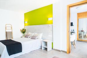 a bedroom with a white bed and a green wall at Dunas Club - Hotel & Apartamentos in Corralejo