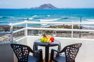 uma mesa com uma taça de frutas e taças de vinho em Dunas Club - Hotel & Apartamentos em Corralejo