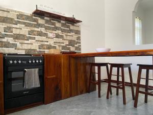 una cucina con piano cottura e un bar con sgabelli di Maisha Villa Nungwi a Banda Kuu