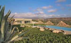 a resort with a swimming pool and some grass at Beachfront villa Komos with heated pool in Kalamaki