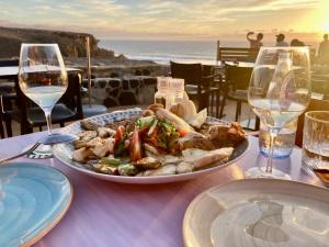 a plate of food on a table with wine glasses at Lugar del Sol in Costa Calma