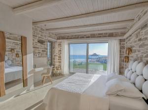 a bedroom with a bed and a view of the ocean at Beachfront villa Komos with heated pool in Kalamaki +23 photos
