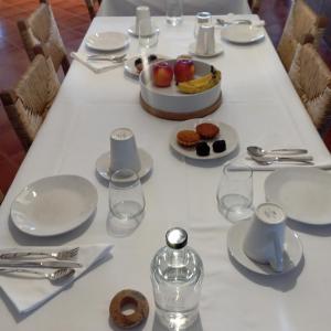 uma mesa com pratos brancos, copos e comida. em Quinta Marugo Retreats em Serpa
