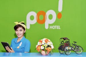 una donna seduta a un tavolo con fiori e una bicicletta di POP! Hotel Malioboro - Yogyakarta a Yogyakarta