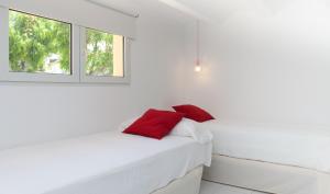 a white bedroom with red pillows on a bed at MR Hotelet de la Raconà & Apartments in Denia