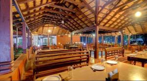 a restaurant with wooden pews and tables and chairs at Lazo Areca Resort , Coorg in Madikeri
