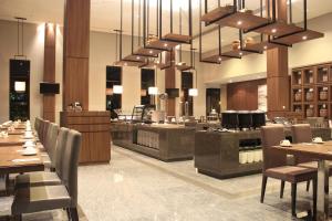 a restaurant with tables and chairs and a large chandelier at I Hotel Baloi Batam in Nagoya