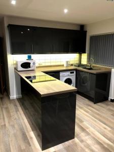 a kitchen with black cabinets and a counter top at Coastal bungalow, sleeps 5 and ideal for walkers in Amlwch