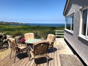 a patio with three chairs and a table on a deck at Coastal bungalow, sleeps 5 and ideal for walkers in Amlwch