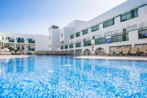 a large swimming pool in front of a building at Dunas Club - Hotel & Apartamentos in Corralejo