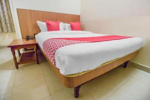 a bedroom with a large bed with red pillows and a table at Super OYO Hotel New Platinum opp New malakpet metro station in Hyderabad