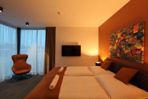 ブラチスラヴァにあるPonton Roomsの大きなベッドと椅子が備わるホテルルームです。
