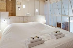 ein weißes Bett mit zwei gefalteten Handtüchern darauf in der Unterkunft Large atypical flat at the heart of Montpellier - Welkeys in Montpellier