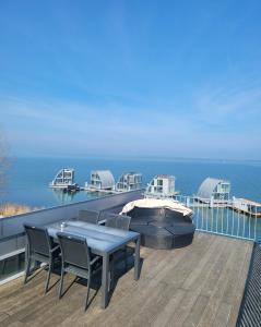 eine Terrasse mit einem Tisch, Stühlen und Meerblick in der Unterkunft Open-Water-Resort in Geierswalde